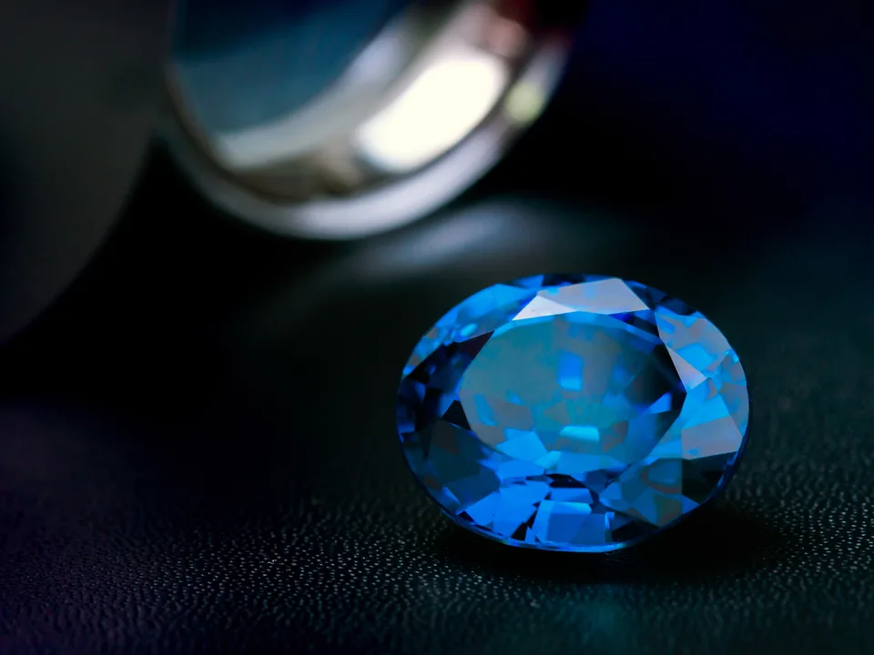 A blue oval gem under a jeweler’s loupe