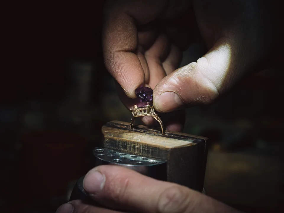 A jeweler’s hands setting a gem into a ring at the bench