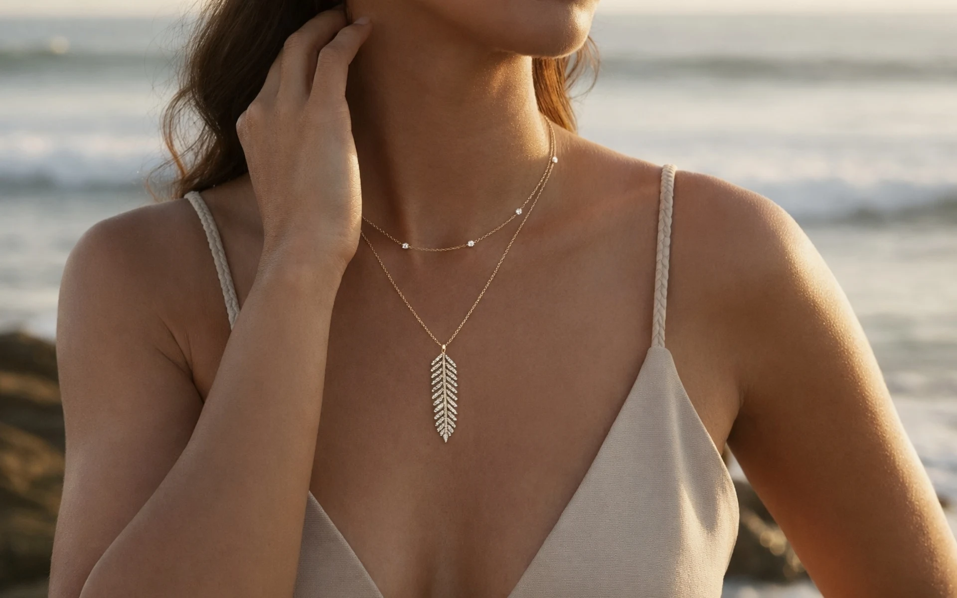 A woman wearing a fine pendant necklace by the sea