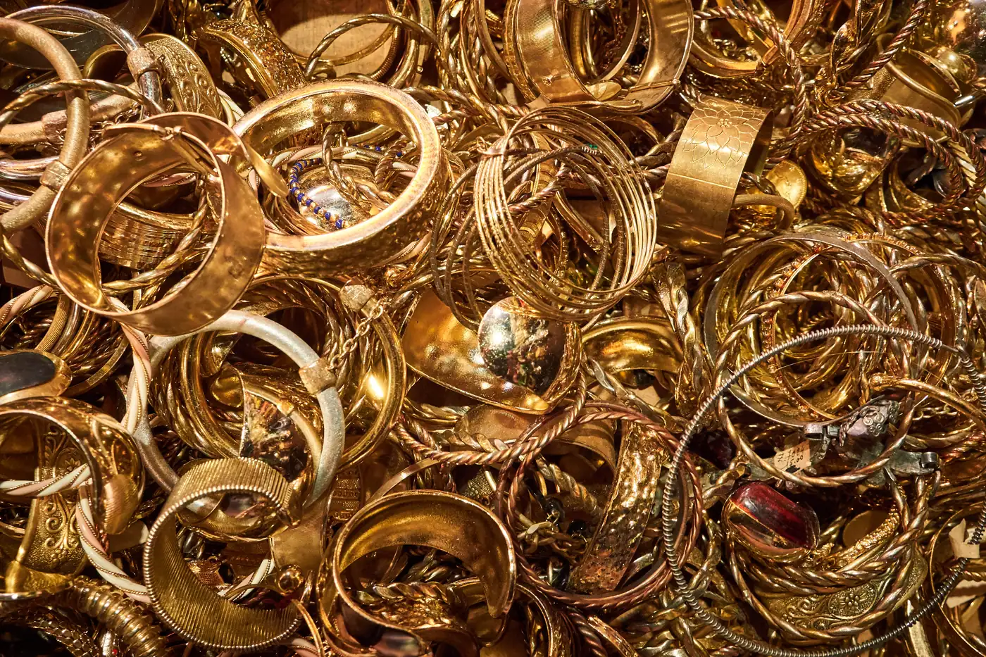 A dense pile of gold bangles and cuffs, worn and engraved