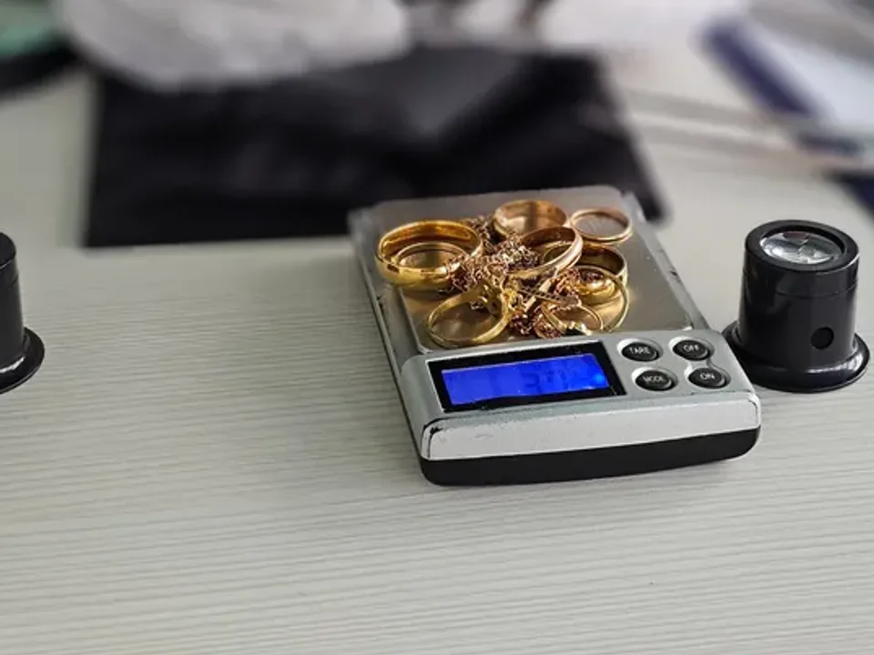 Gold rings on a pocket scale with loupes beside it