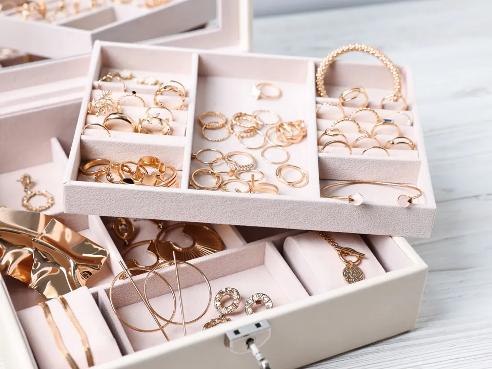 An open jewelry box with trays of gold rings and bracelets