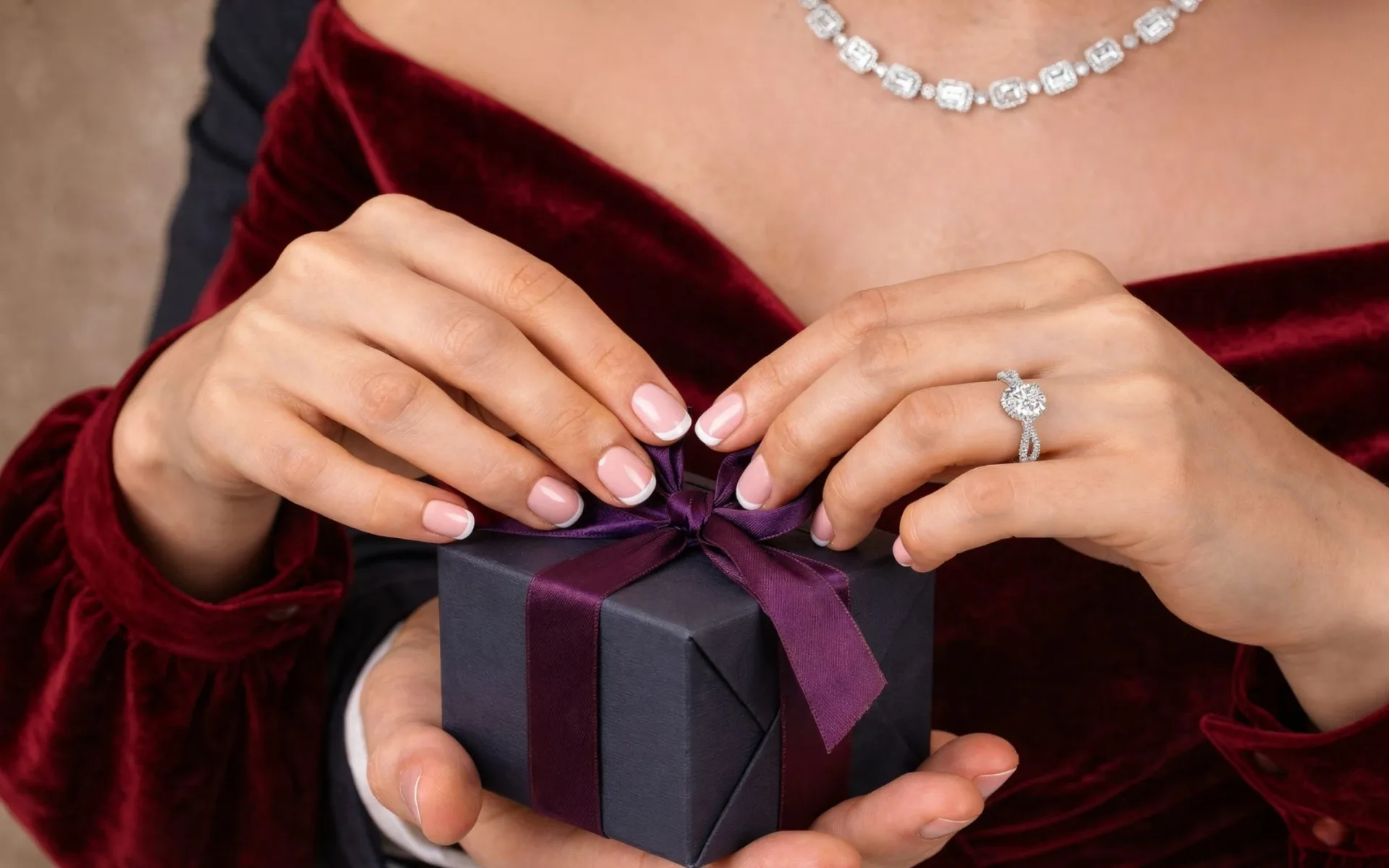 Hands untying a purple ribbon on a small gift box