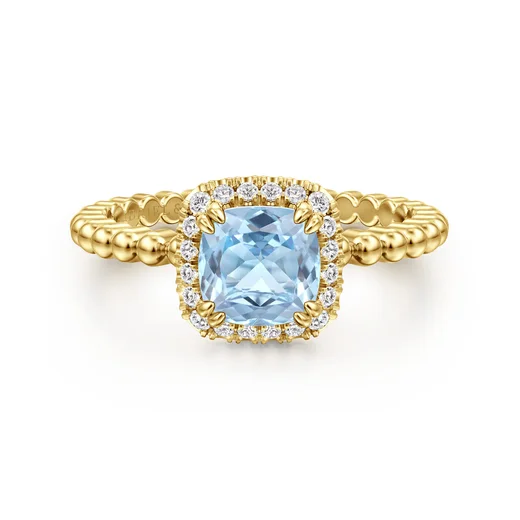 A cushion-cut aquamarine ring with a diamond halo in 14K yellow gold, by Gabriel & Co.