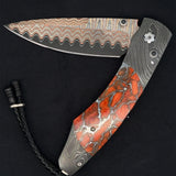 William Henry Knife The Spearpoint ‘Liquid Sky’ features a frame in hand-forged 'Twist' damascus by Chad Nichols, inlaid with Zinc Matrix apple coral. The blade is 'Copper Wave' damascus with a VG5 core; the one-hand button lock and the thumb stud are set