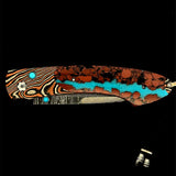William Henry Knife The Spearpoint 'Chuska' features a beautiful frame in 'Twist' Mokume by Mike Sakmar, inlaid with vein turquoise. The blade is William Henry's signature 'Wave' damascus steel with VG-10 core. The one-hand button lock and the thumb stud