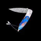 The Monarch ‘Blue Grove' William Henry Knife with Aerospace Grade Titanium with Mini Pine Cones Set in Resin and 'Intrepid' Damascus Steel Blade.