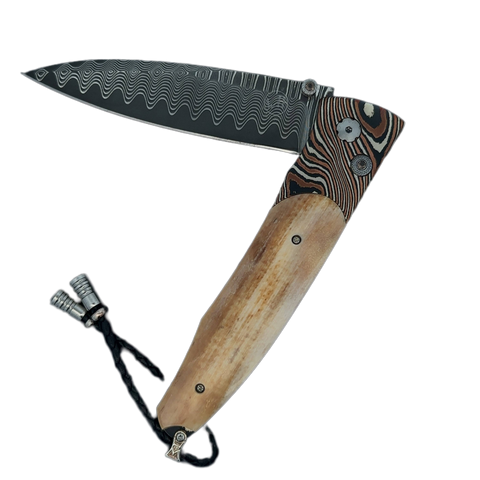 William Henry Knife The Gentac ‘Eventide’ features a beautiful frame in hand-forged 'Twist' mokume gane, inlaid with bark, or outer section, of a 10,000 year-old fossil Woolly Mammoth tusk . The blade is 'Wave' damascus steel with a VG-10 core; the one-ha